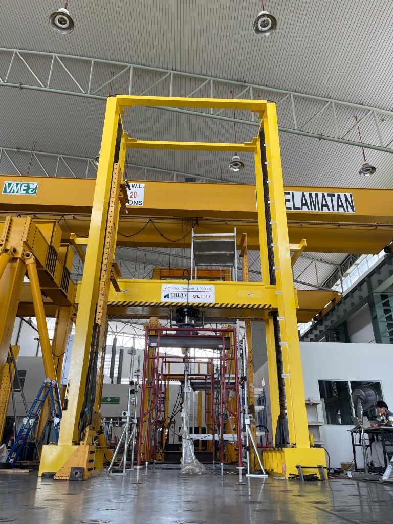 Yellow structural test frame with actuator system in a testing facility